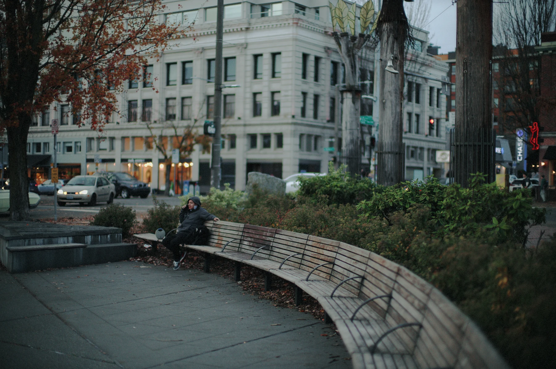 a woman on a curved park bench at dusk